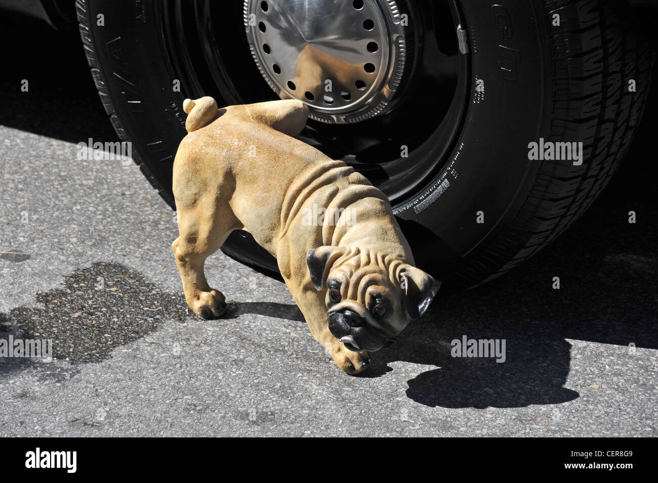 Dog urinating on a car tyre, model of a dog peeing on a car wheel Stock