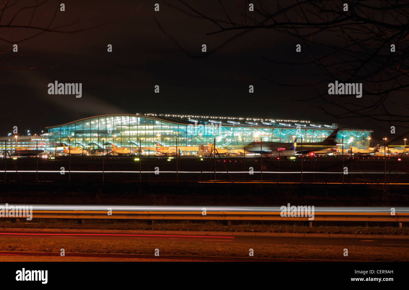 Aircraft at the boarding gates outside Terminal Five at Heathrow airport at night. Stock Photo