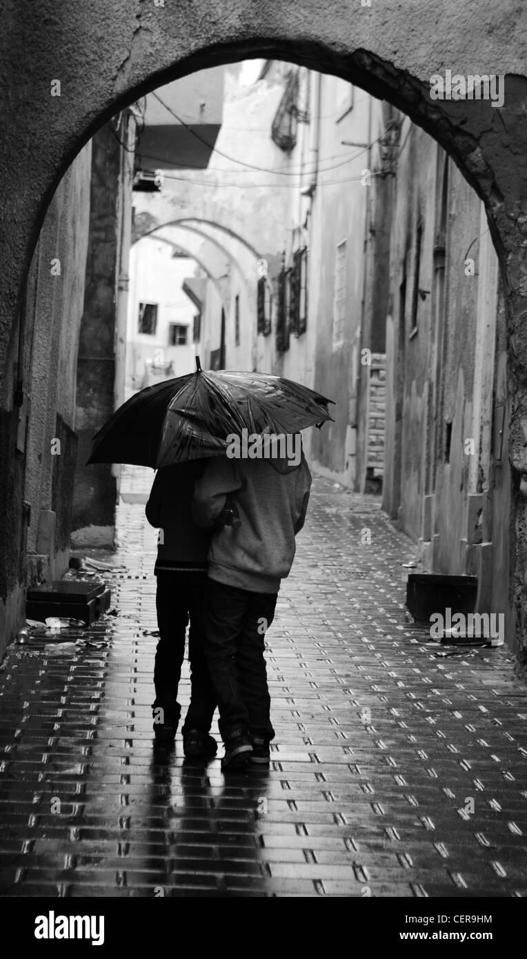 Two young boys share umbrella during a rainy day in the Medina of Tripoli, Libya Stock Photo