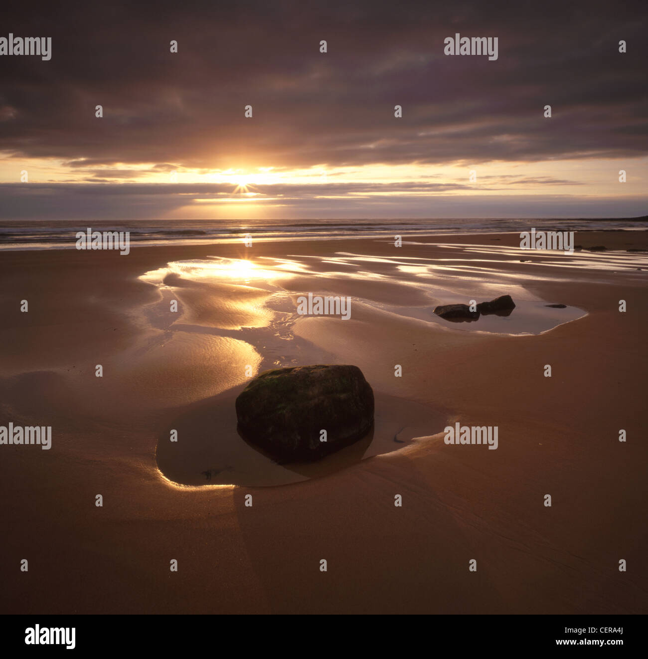 Sunrise over the North Sea at Embleton Bay. Dunstanburgh Castle stands at the southern end of Embleton Bay. Stock Photo