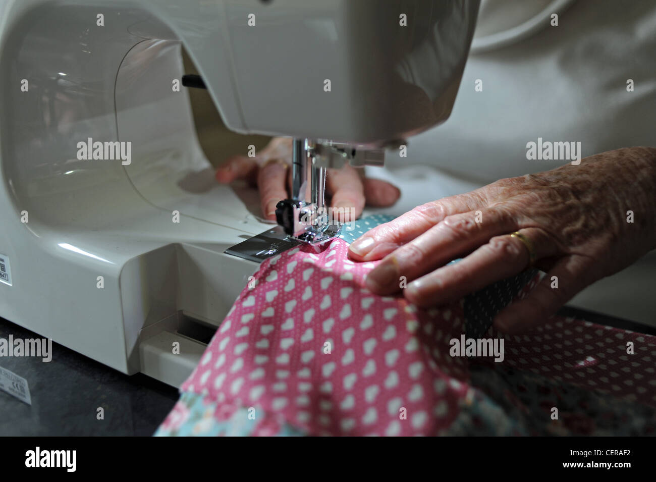Mature woman in her 70s using a Janome sewing machine making a quilt at home UK Stock Photo