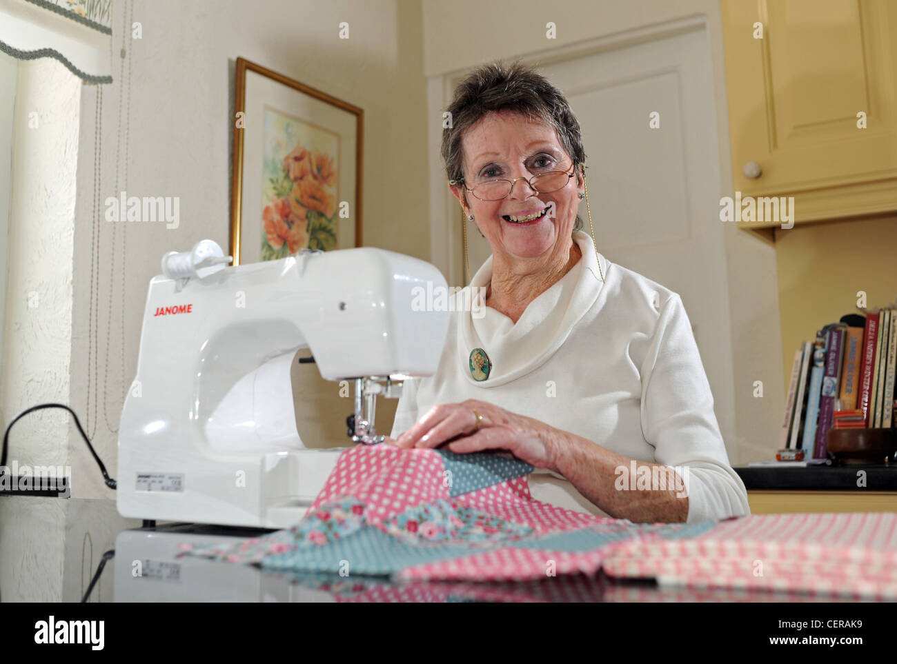 Mature woman in her 70s using a Janome sewing machine making a quilt at