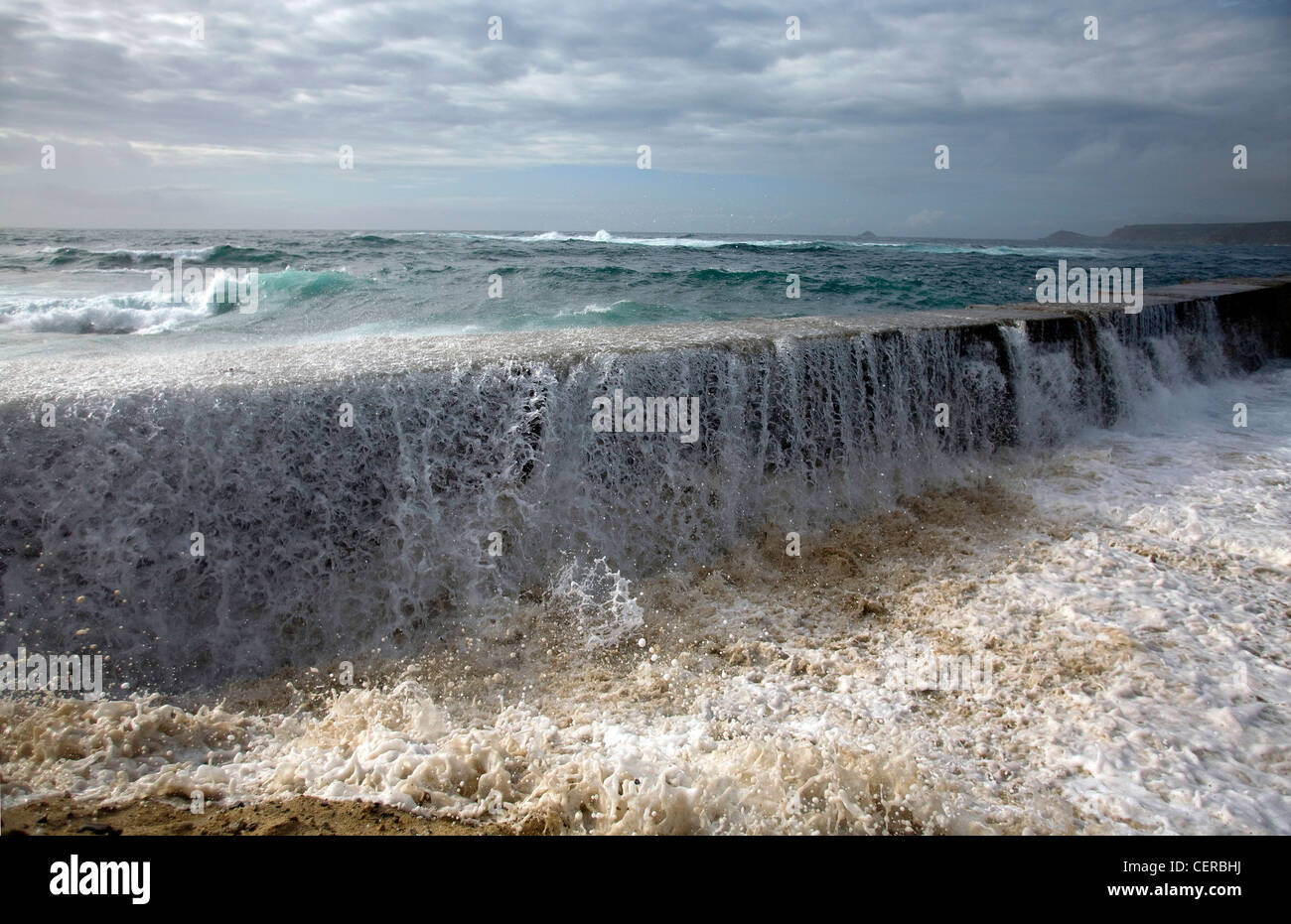 Atlantic storms driving tidal surge and waves crashing forcefully over the breakwater with dramatic force, destroying the beach. Stock Photo