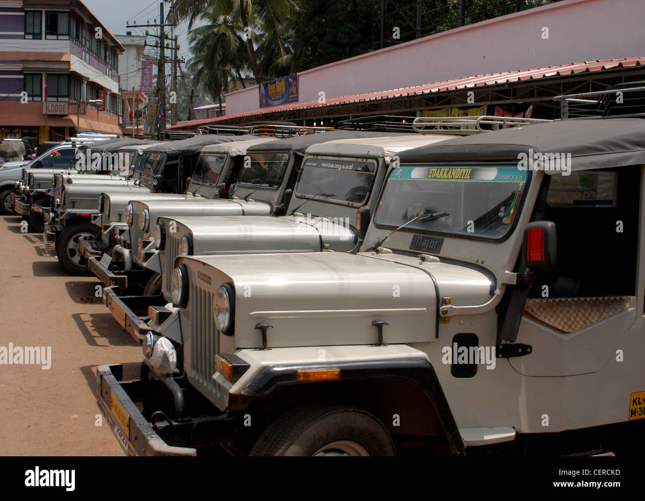 Fleet of private Mahindra Willys Jeep silver taxis outside temple in Kerala district waiting for pilgrims to take them home. Stock Photo