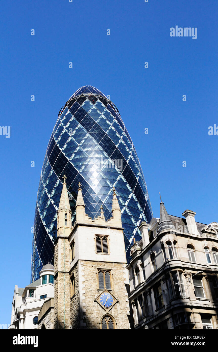 30 St Mary Axe, the Swiss Re Building known as The Gherkin, towering above St Andrew Undershaft in the City of London. Stock Photo