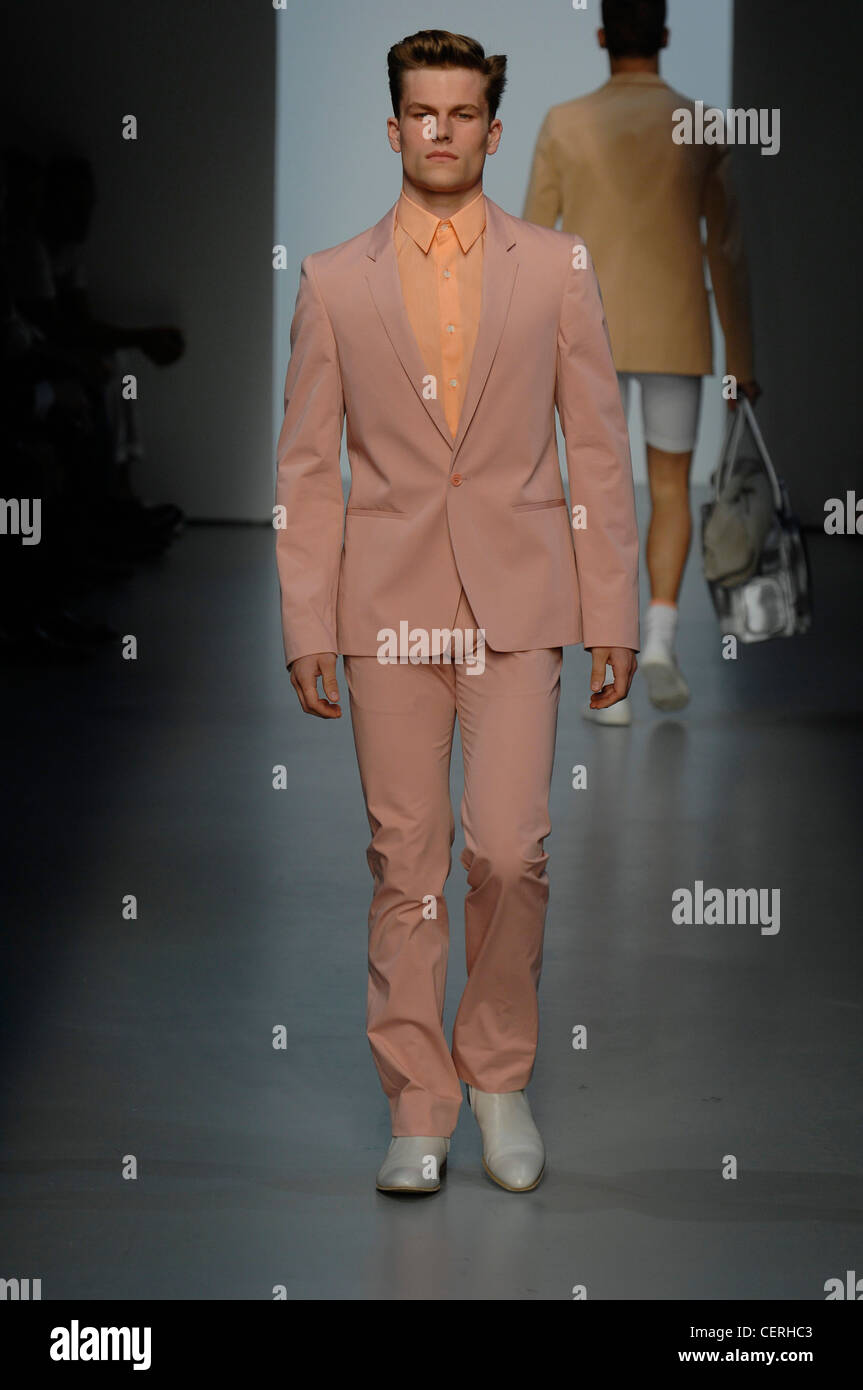 Calvin Klein Milan Menswear Ready to Wear Spring Summer Model pink suit and peach shirt with white shoes Stock Photo