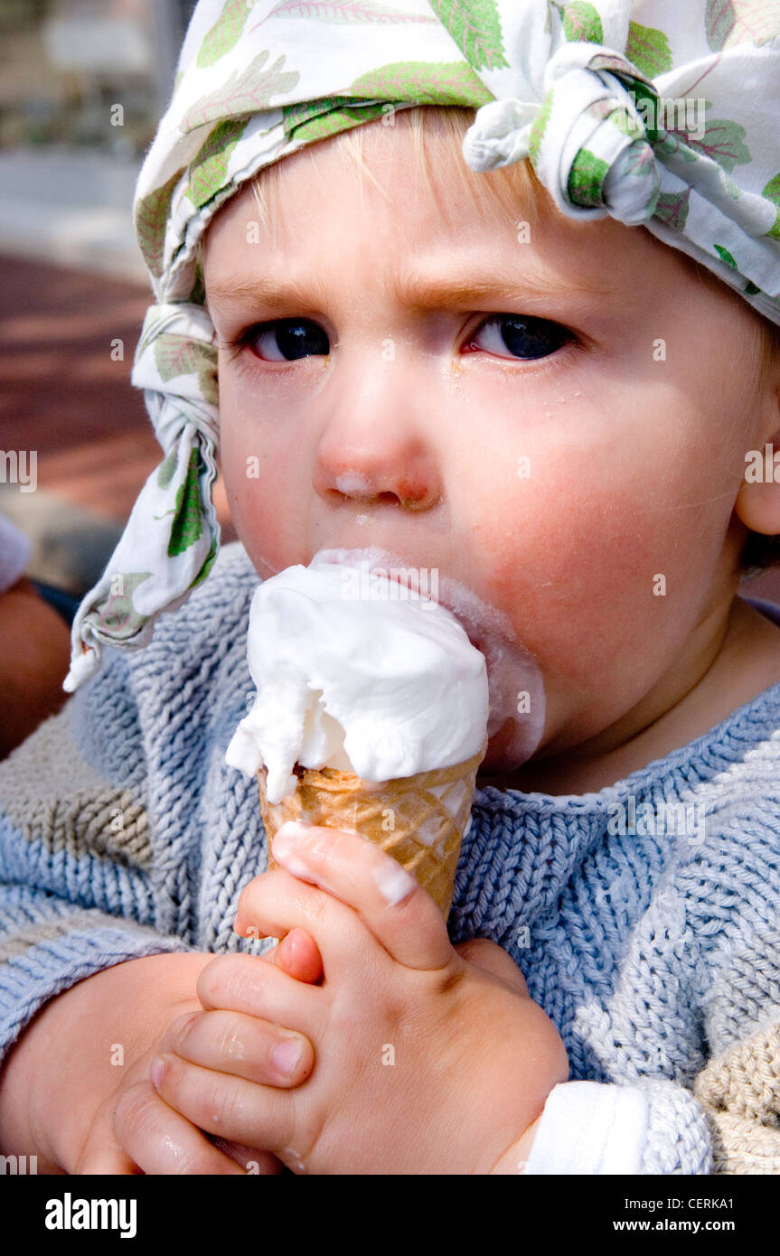 Male child wearing handkerchief on head eating ice creme cone Stock