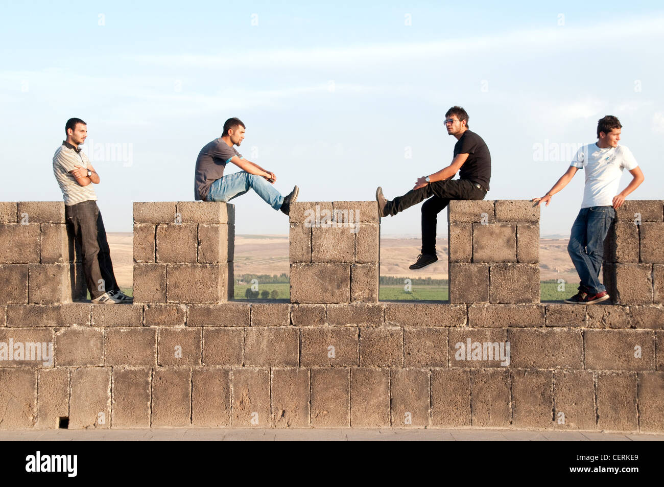 A group of four young Kurdish men sit atop the old walls and fortress of the city of Diyarbakir, in eastern Anatolia, southeastern Turkey. Stock Photo