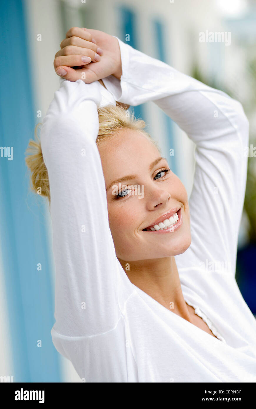 Female wearing white top smiling with arms up above head Stock Photo ...