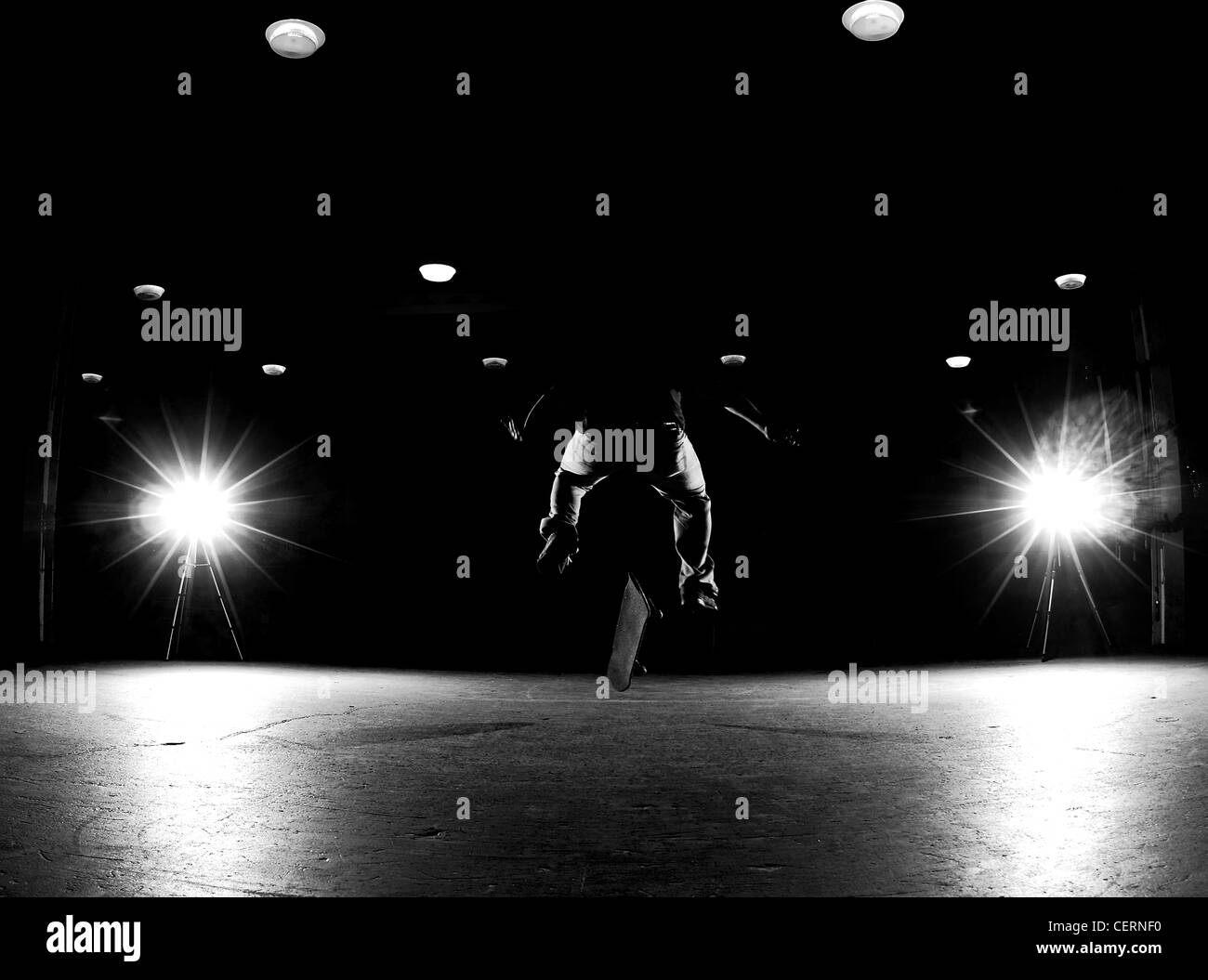 A black and white photo of a skateboarder performing a flip trick. Stock Photo