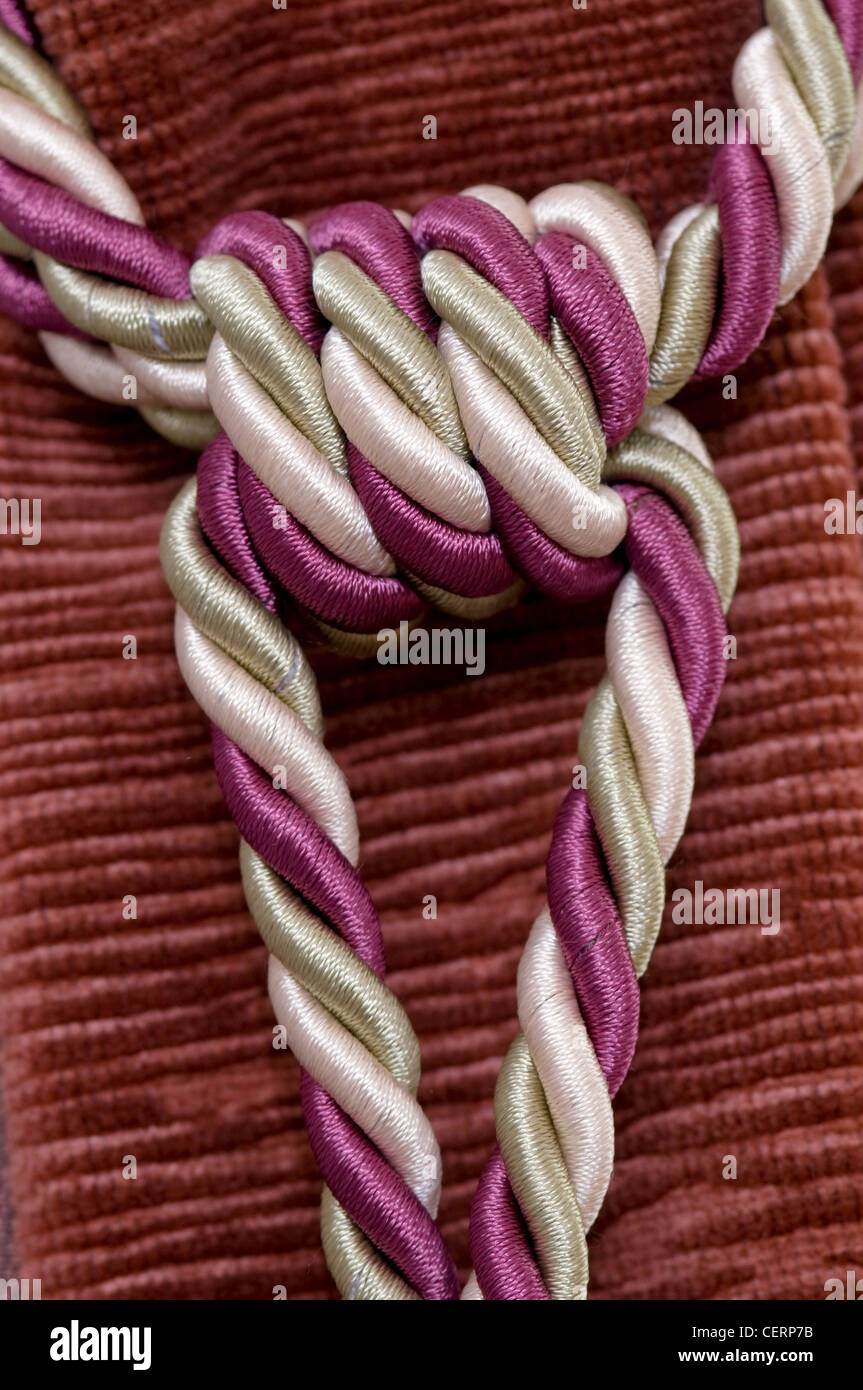 rope connected to a node lies on colored fabric Stock Photo
