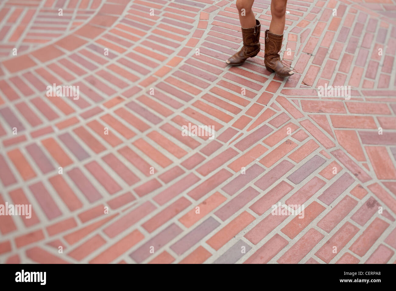 child legs in cowboy boots walking on brick design Stock Photo