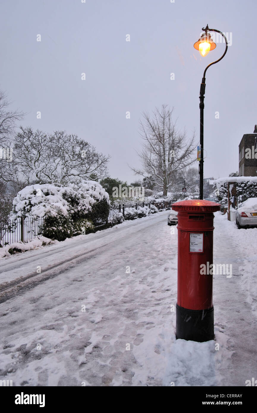 A London post box and street light surrounded by snow. Stock Photo