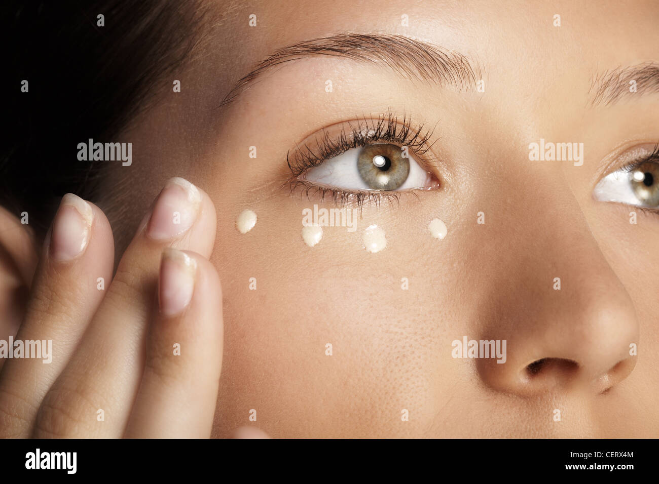 Female with four dots of cream under her eye Stock Photo