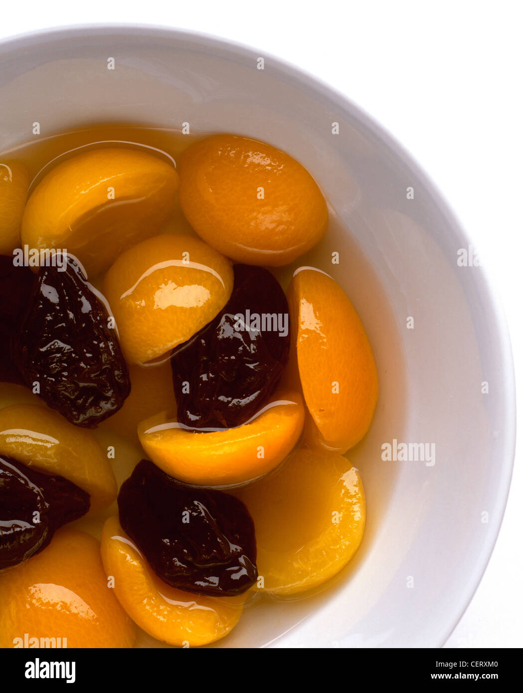 A still life bowl of tinned apricot halves in syrup, with dried prunes Stock Photo