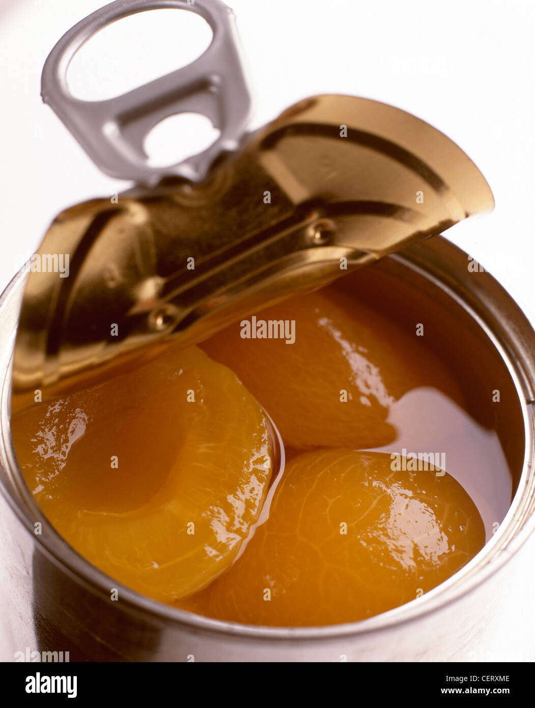 A half opened tin of apricot halves in syrup Stock Photo