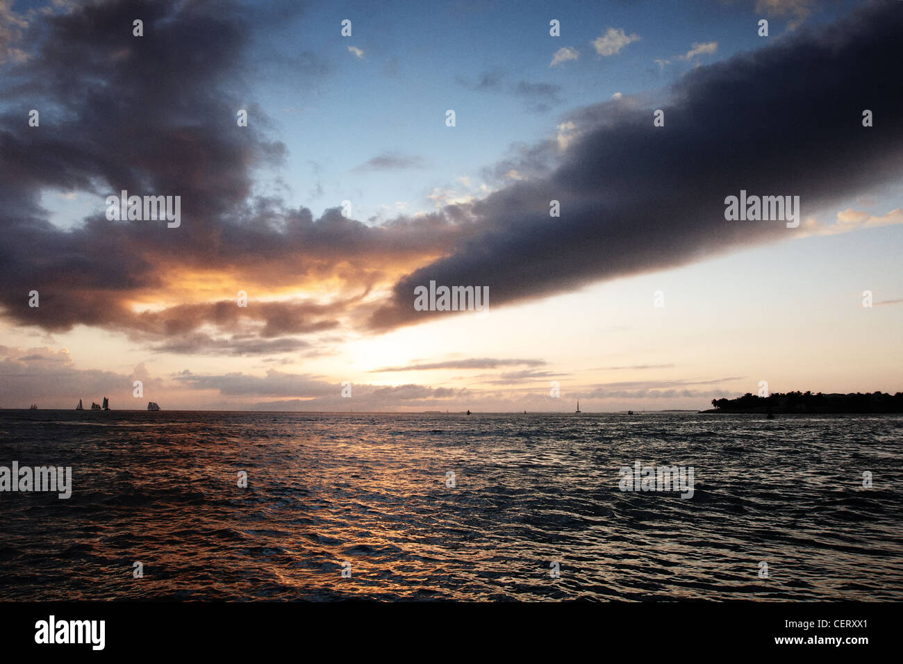 Ships on the horizon with the sun setting Stock Photo - Alamy