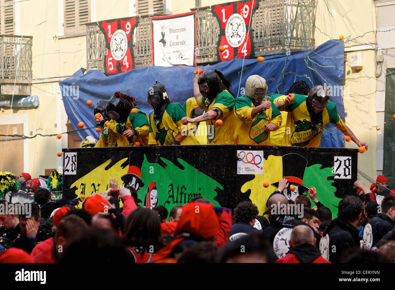 Crowds throwing oranges at the carriage during Ivrea Carnival's 'Battle of Oranges' (La battaglia delle arance) Stock Photo