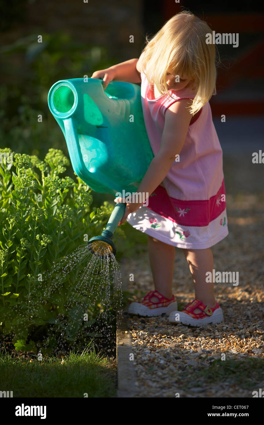 child (young girl) watering garden, Dorset, England, UK Stock Photo Alamy