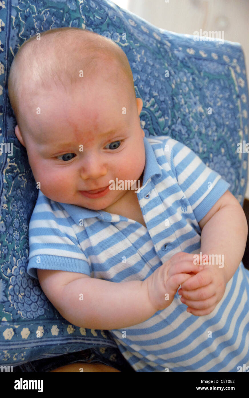 Male infant wearing a blue stripy t shirt resting his head on blue pillow Stock Photo