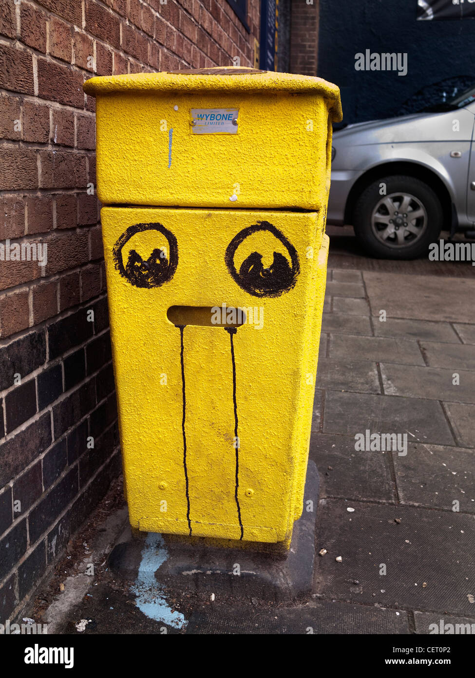 Yellow wheelie bin with painted face. Stock Photo