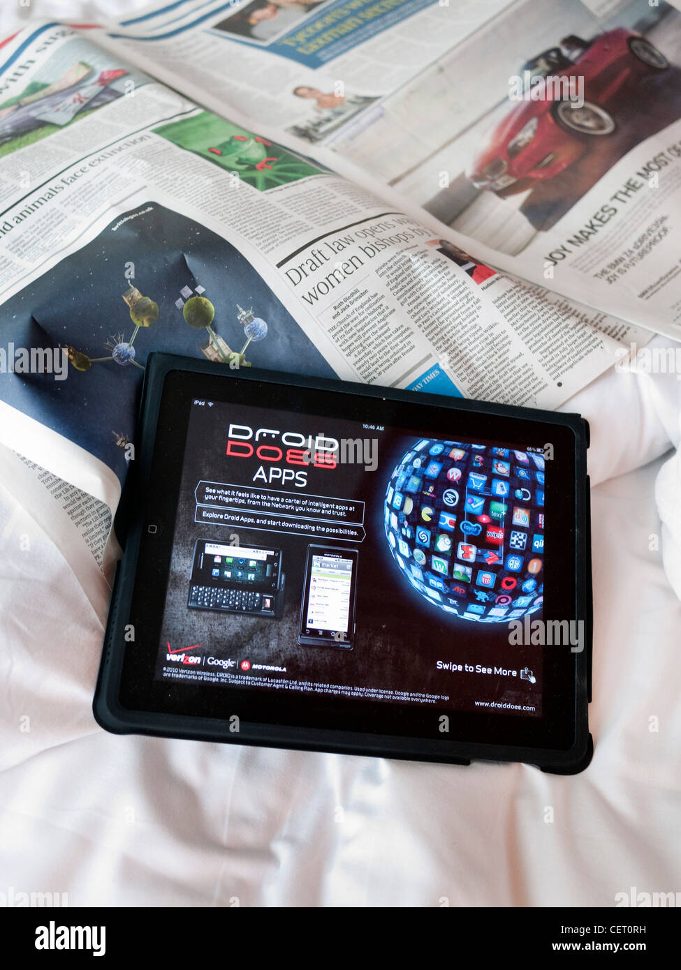 Apple iPad with sunday papers on unmade bed Stock Photo