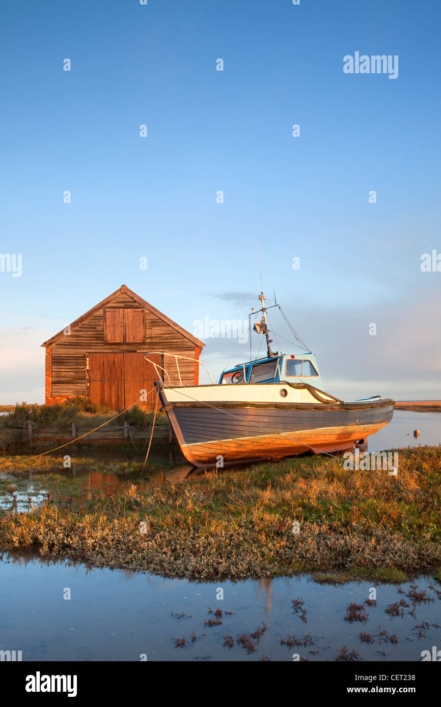 A boat moored by the old coal shed at first light at Thornham Harbour