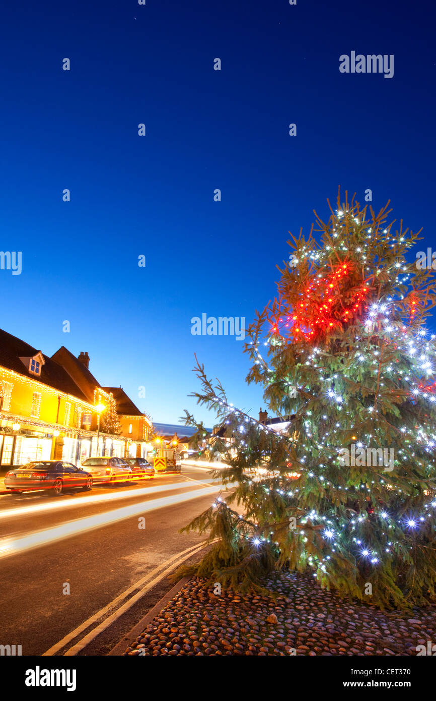 Light trails from traffic passing a Christmas tree with decorations by
