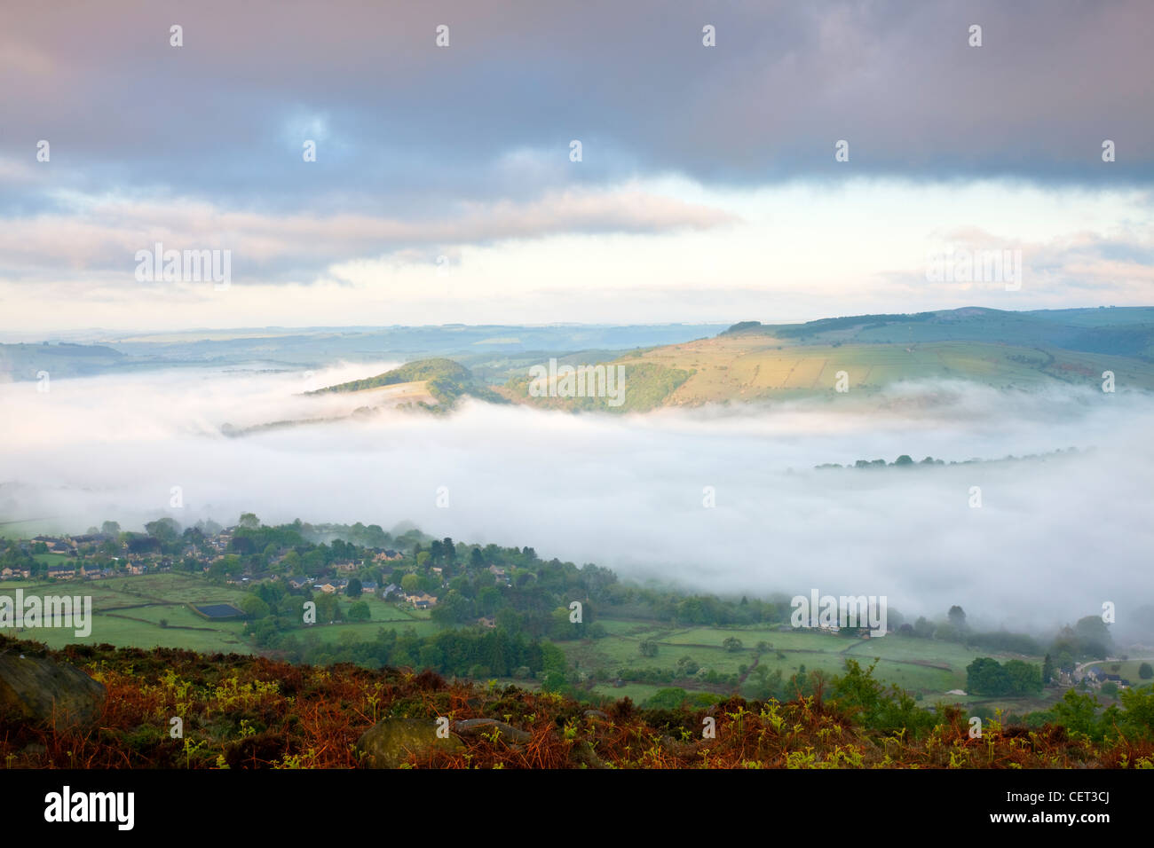 Mist over the village of Calver viewed at first light from Curbar Edge in the Peak District National Park. Stock Photo