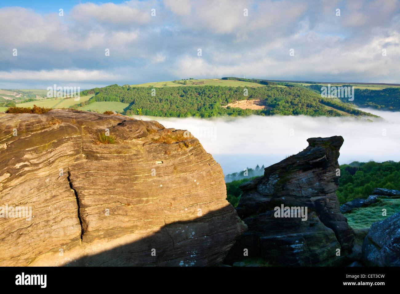 Low lying mist in the valley below Froggatt Edge, a gritstone escarpment, at dawn in the Peak District National Park. Stock Photo