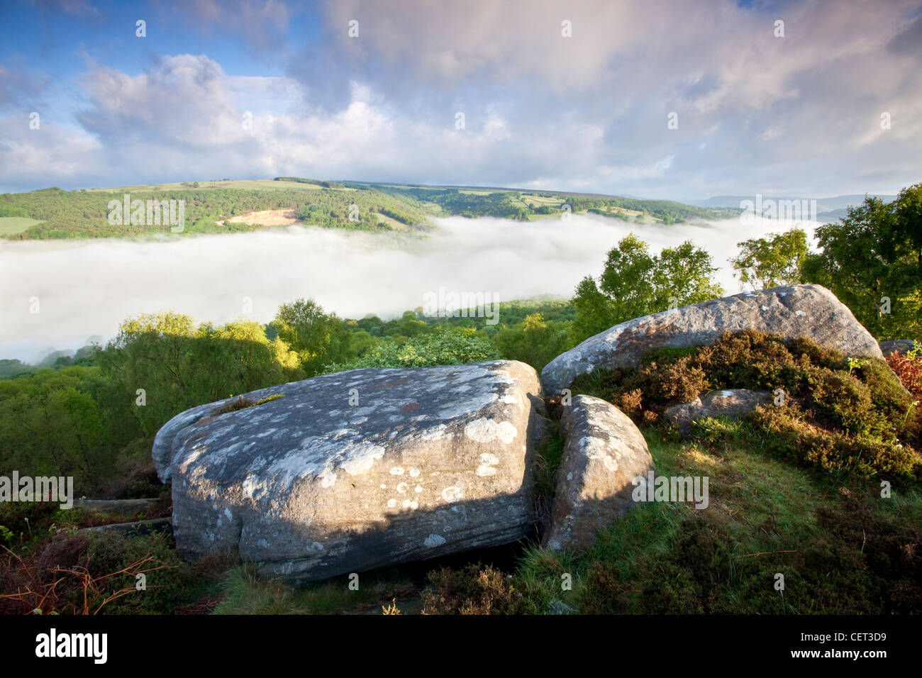 Low lying mist in the valley below Froggatt Edge, a gritstone escarpment, at dawn in the Peak District National Park. Stock Photo