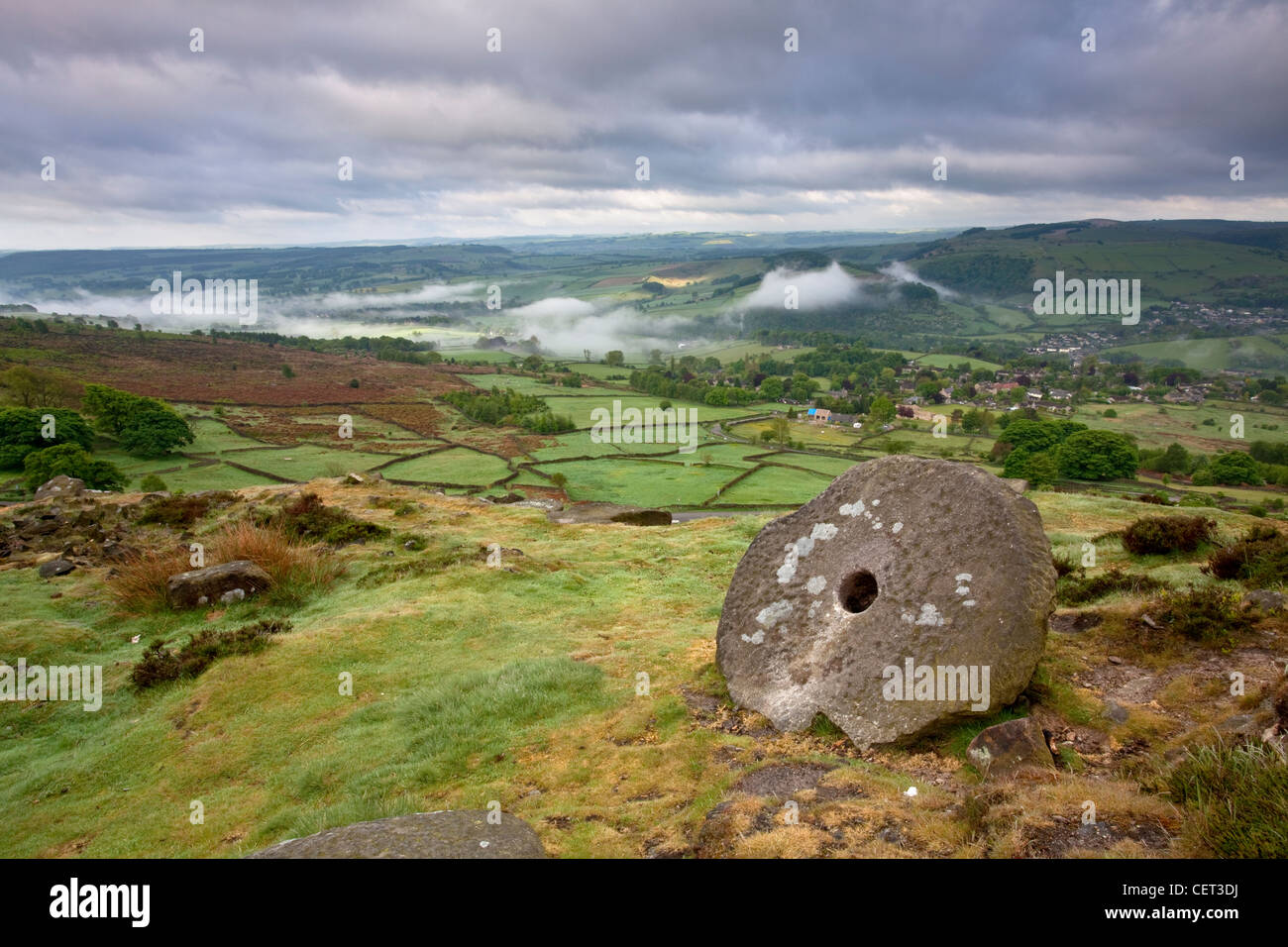 View at dawn from an abandoned millstone on Curbar edge to low lying mist in the valley below. Stock Photo