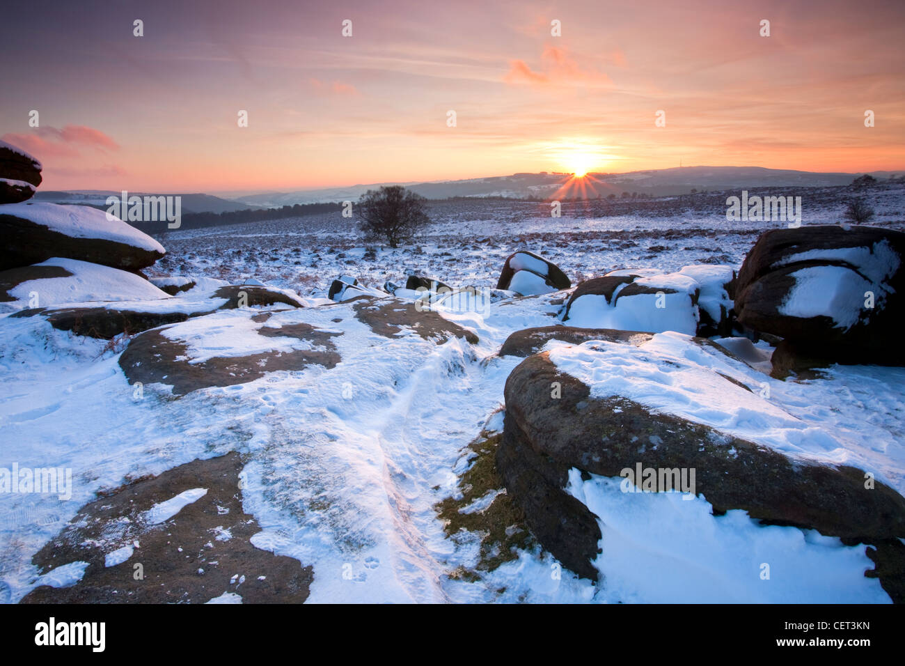 Sunset viewed from snow covered Over Owler Tor in the Peak District National Park. Stock Photo