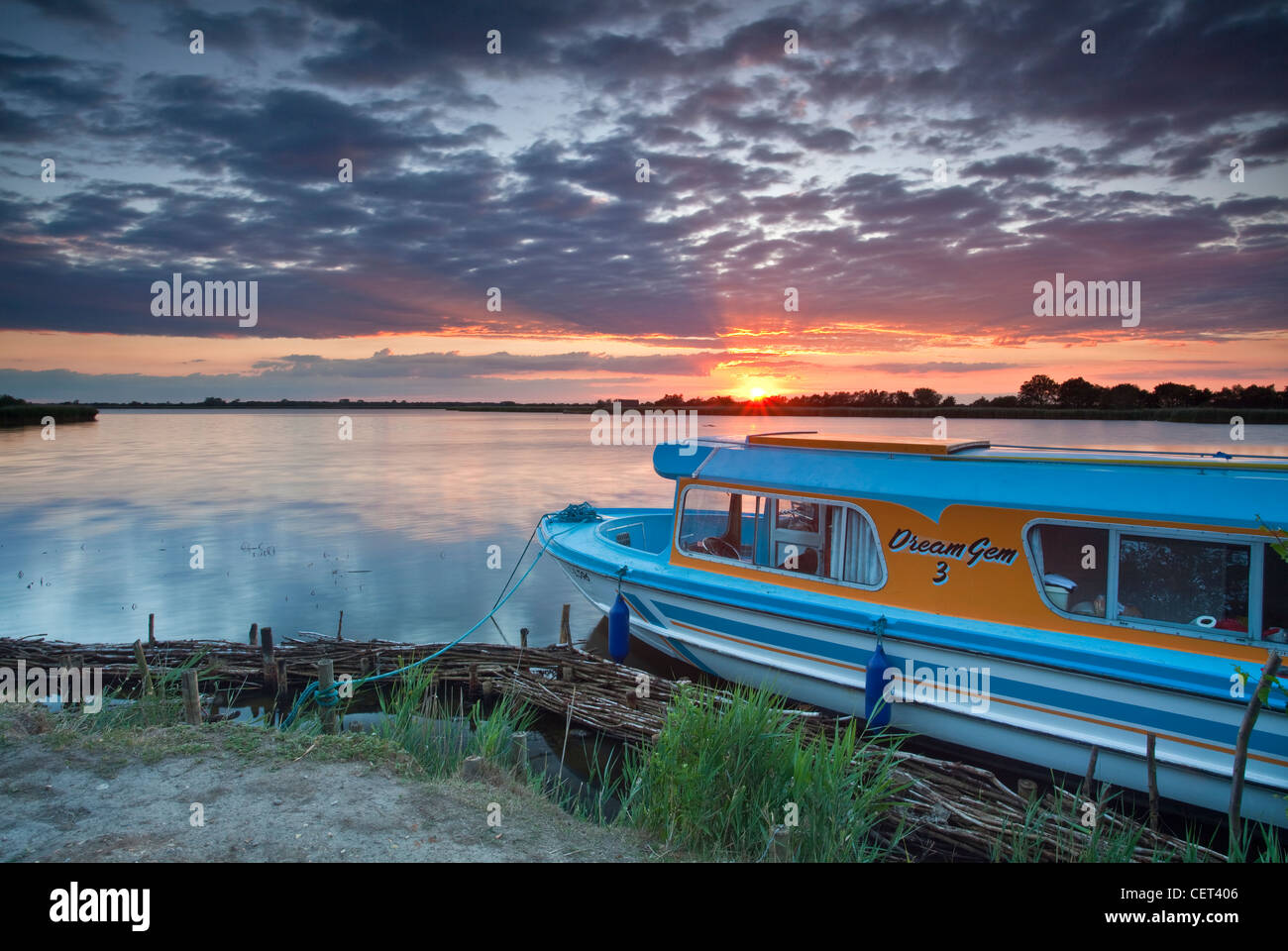 A Norfolk Broads cruiser moored on the edge of Horsey Mere at sunset on the Norfolk Broads. Stock Photo