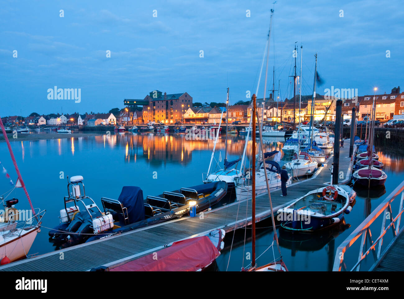 Boats moored alongside a jetty in the quay at Wells-next-the-Sea on the North Norfolk coast at night. Stock Photo