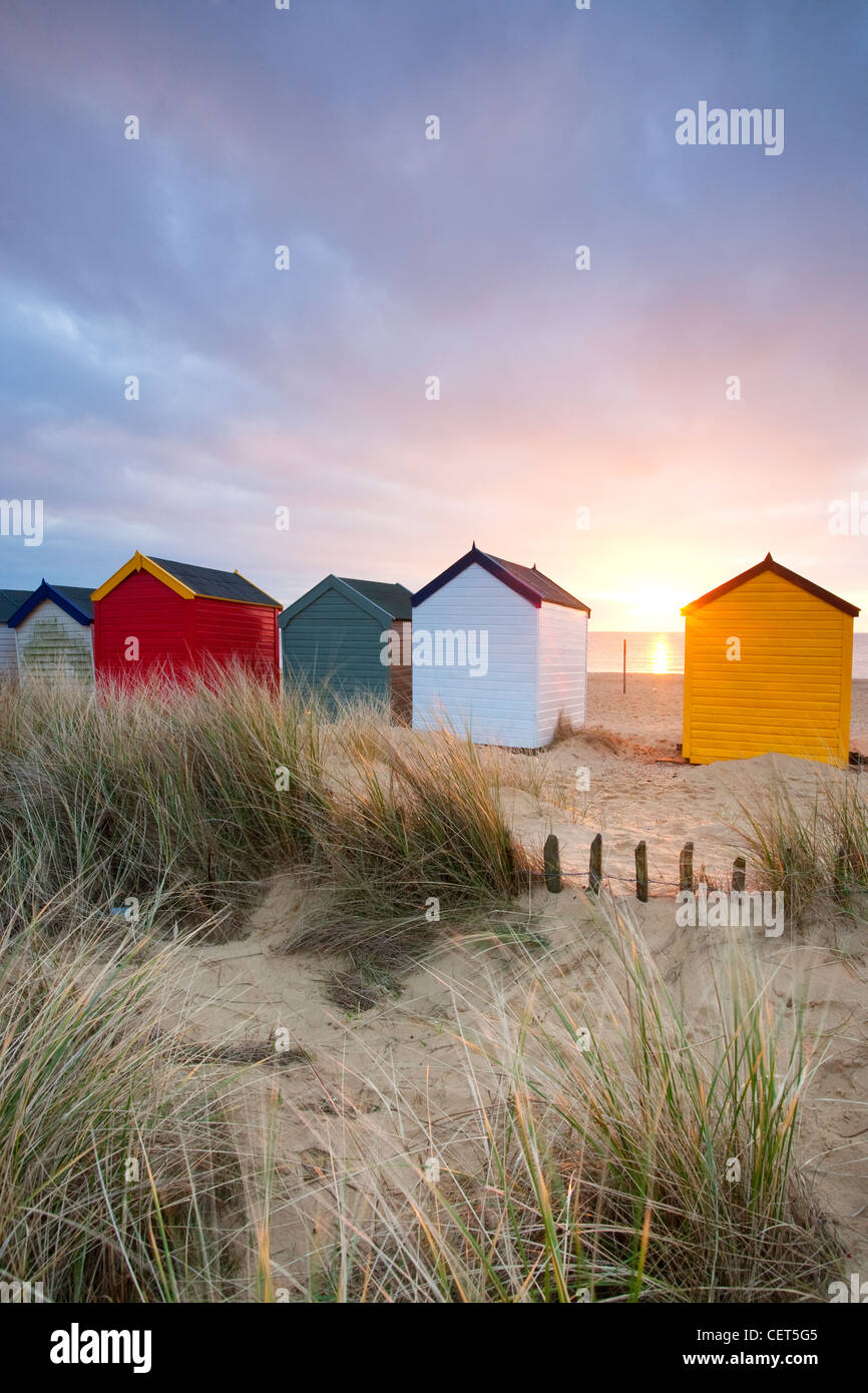 Dawn over sand dunes and colourful beach huts along the seafront at Southwold on the Suffolk Coast. Stock Photo