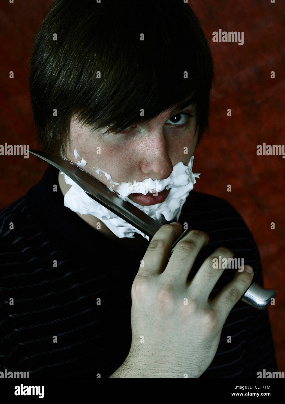 A young man shaving his face with a knife Stock Photo Alamy
