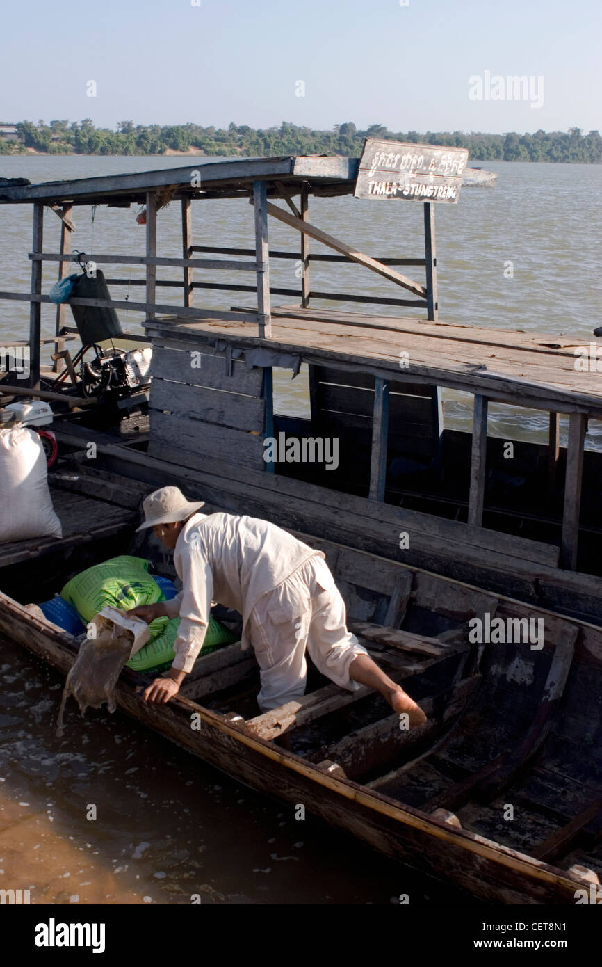 A man is bailing water out of a longtail fishing boat on the Mekong River in Stung Treng, Cambodia. Stock Photo
