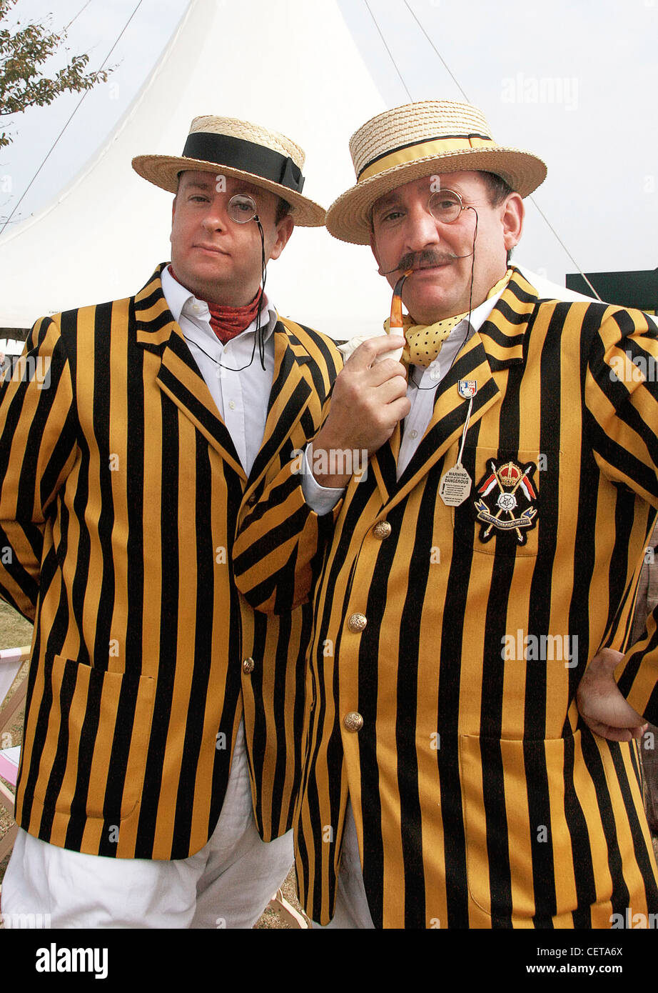 Men in retro outfits with straw hats, monocle eyeglass, pipe and jackets at Goodwood Revival. Stock Photo