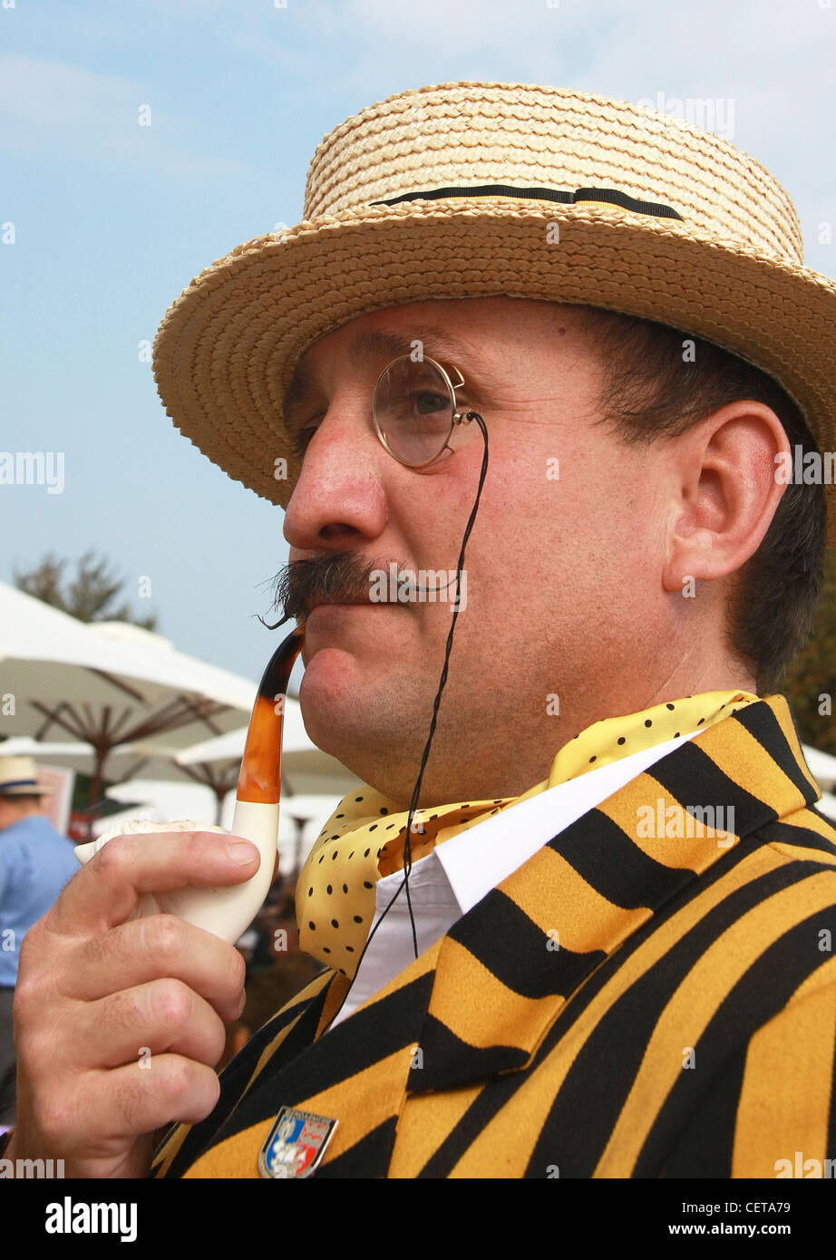 Man with monocle, straw hat and pipe at Goodwood Revival. Stock Photo