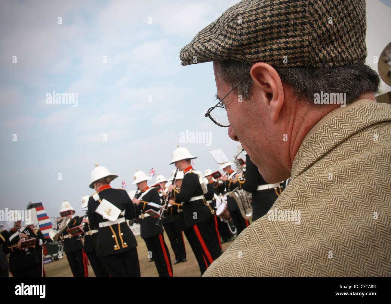 Spectator in cap and blazer watching Military band at Goodwood Revival. Stock Photo