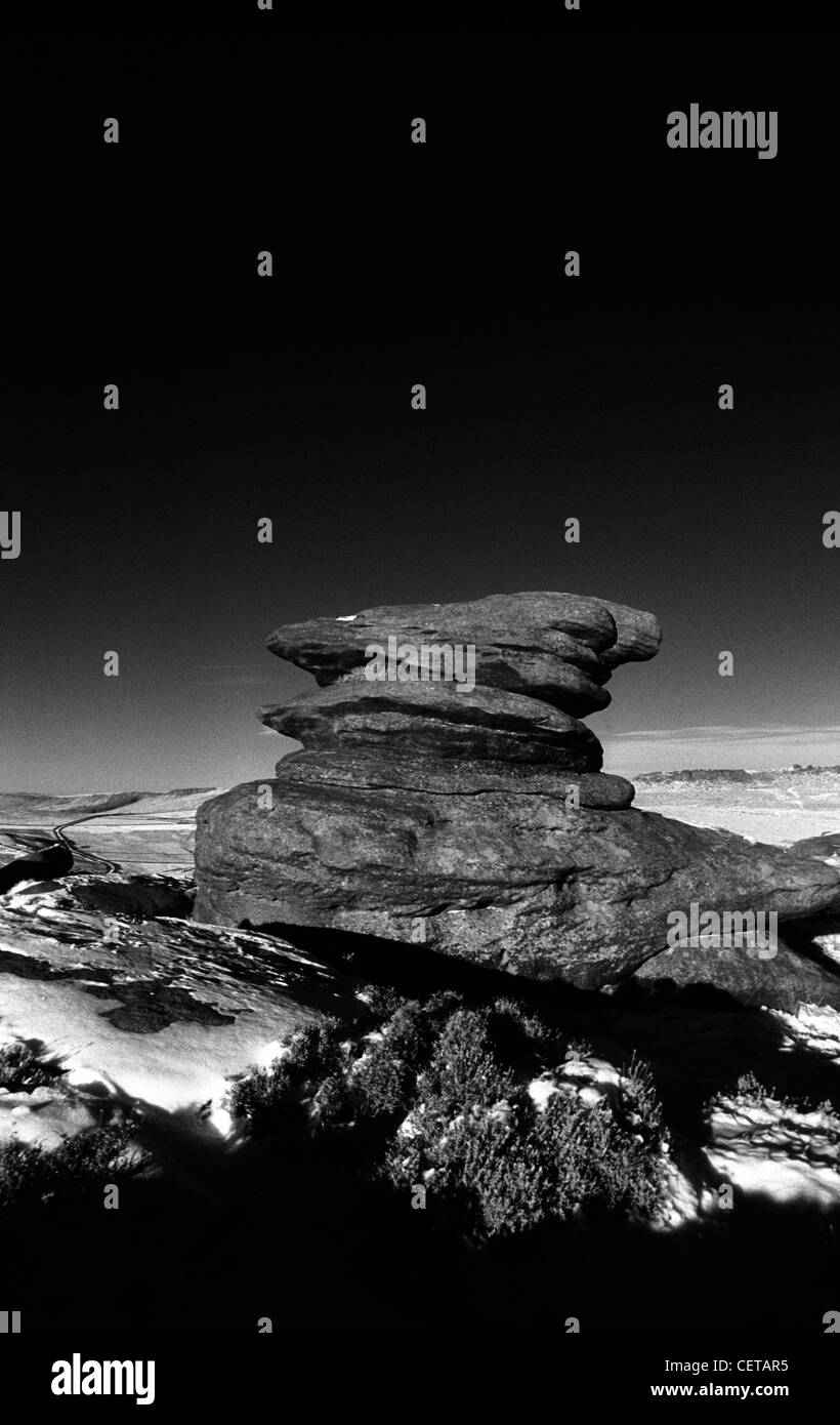 Black and white landscape of dramatic, weathered gritstone rocks and snow near Hathersage, Derbyshire in the Peak District. Stock Photo