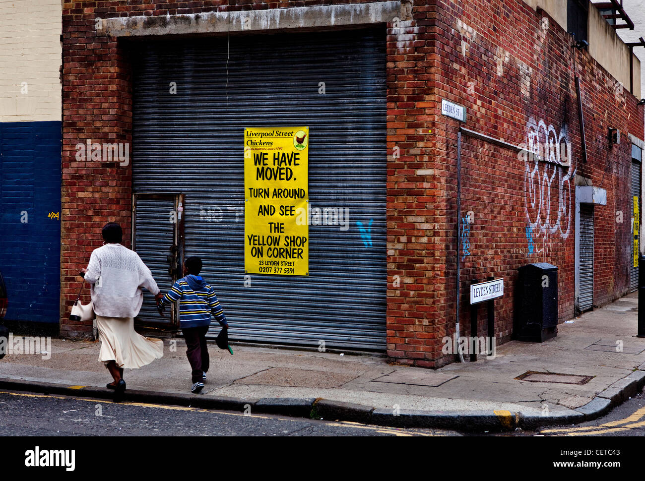 Petticoat lane market, London. Mother & son walk past an empty store. Stock Photo