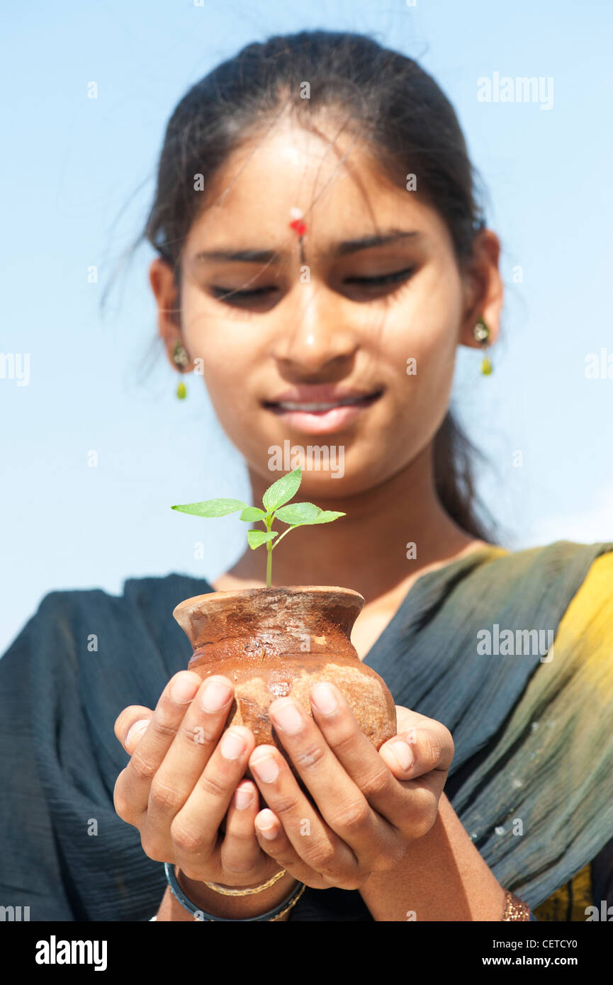 Indian teenage girl holding a plant seedling in a clay pot. India Stock