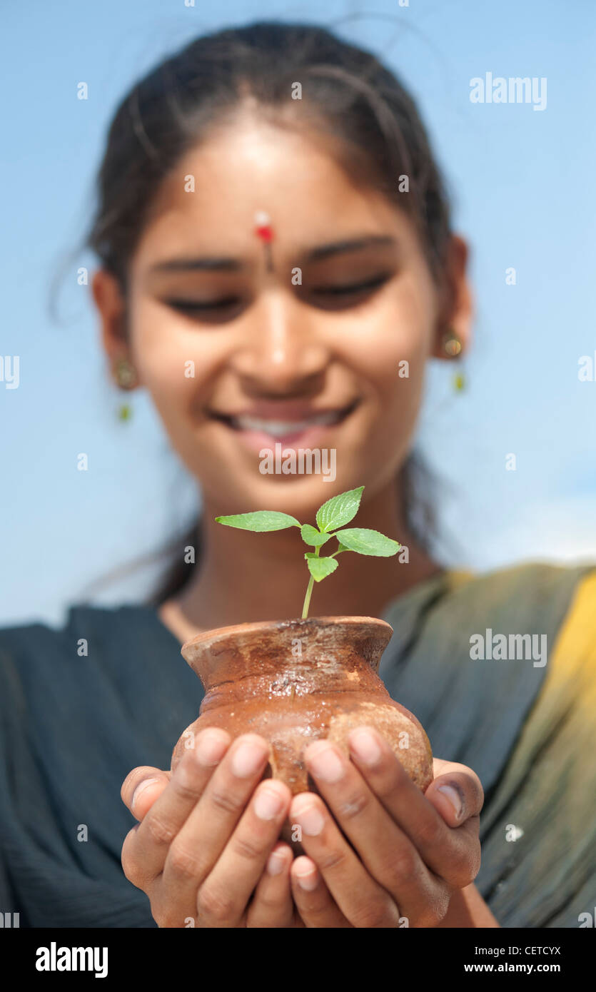 Indian teenage girl holding a plant seedling in a clay pot. India Stock