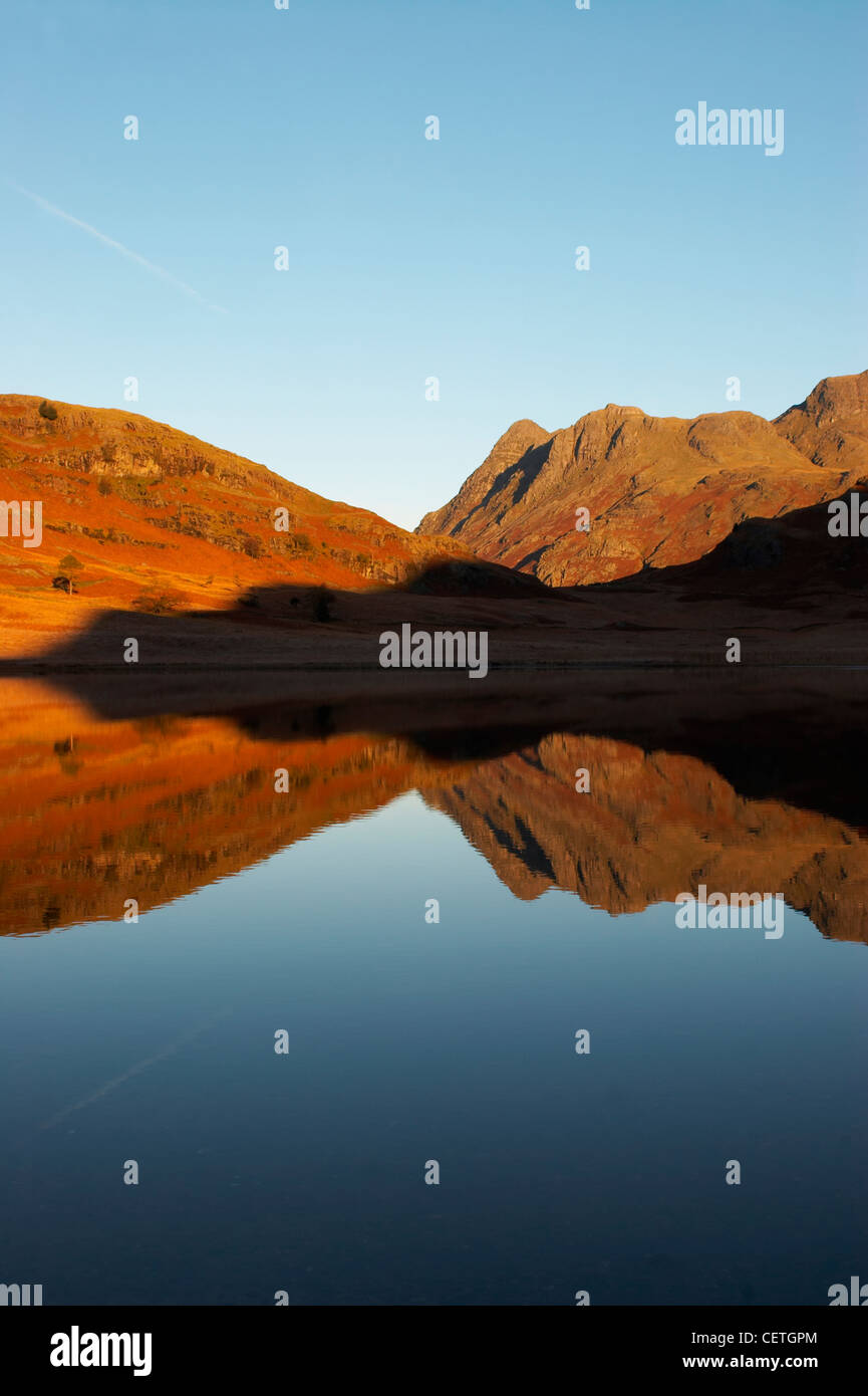 Reflections in Blea Tarn at sunrise. Blea Tarn lies at the top of the pass between Dungeon Ghyll at the head of Great Langdale, Stock Photo