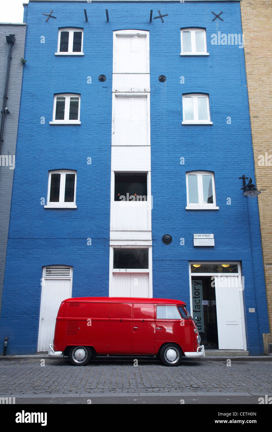 Red VW camper van parked outside blue building on Clink Street. This is the street whose prison gave its name to the expression Stock Photo