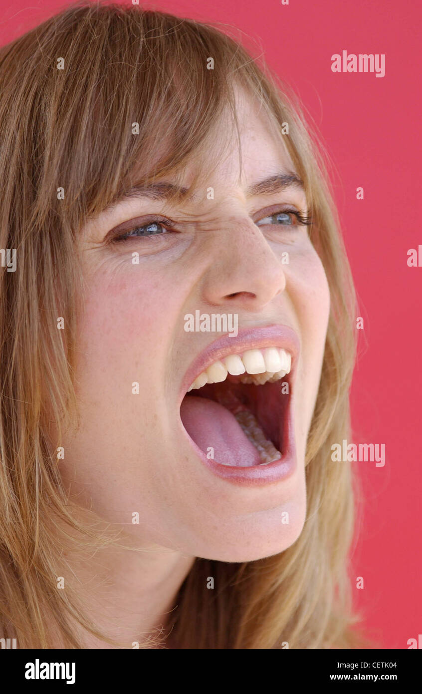 Semi profile of female long light brown hair and fringe wearing subtle eye make up and pink lipstick, mouth open shouting Stock Photo