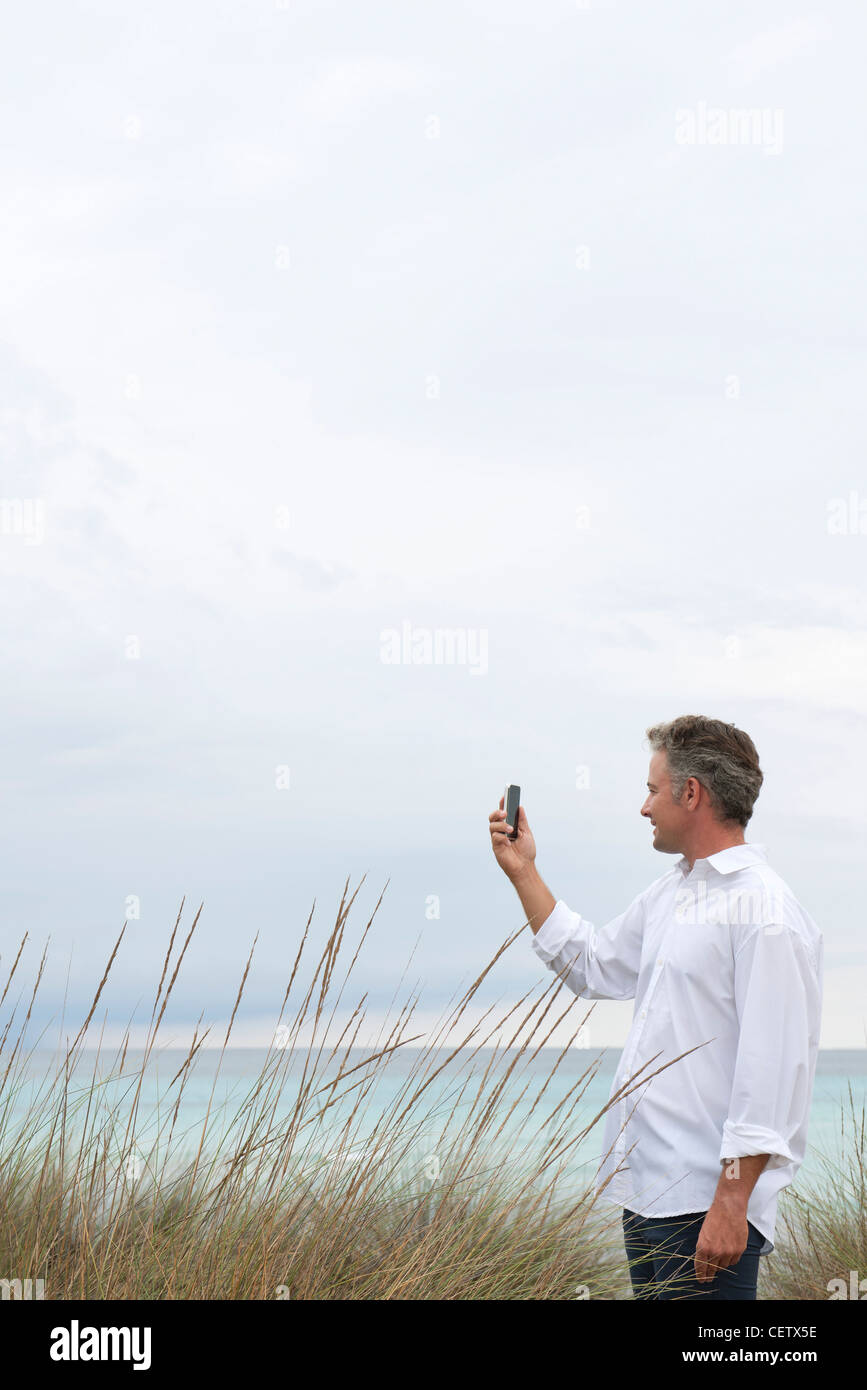 Mature man photographing scenery with cell phone Stock Photo