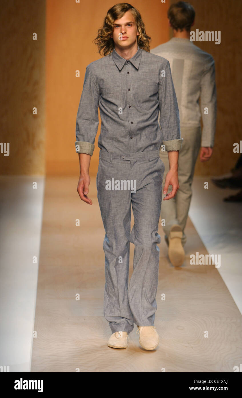 Calvin Klein Milan Menswear S S Long haired male wearing grey long sleeved  shirt rolled up sleeves; and matching grey trousers Stock Photo - Alamy